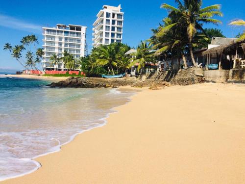 einen Strand mit Palmen und Gebäuden und dem Meer in der Unterkunft SEASHORE Resort & Villa in Talpe