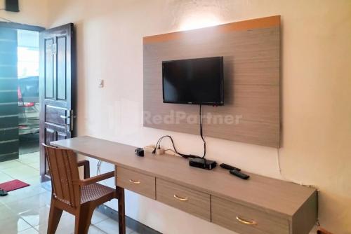 Zimmer mit einem Schreibtisch und einem TV an der Wand in der Unterkunft Rosa Luxury Jagakarsa RedPartner in Jakarta