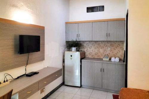 eine Küche mit einem Kühlschrank und einem TV in der Unterkunft Rosa Luxury Jagakarsa RedPartner in Jakarta
