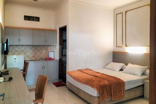 ein Schlafzimmer mit einem Bett und einem Schreibtisch sowie eine Küche in der Unterkunft Rosa Luxury Jagakarsa RedPartner in Jakarta