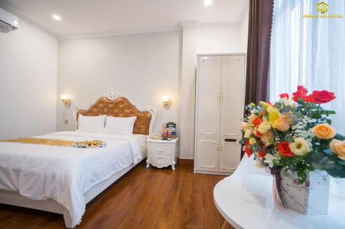 a bedroom with a bed and a vase of flowers at Hoàng Gia Hotel Tuy Hoà in Tuy Hoa