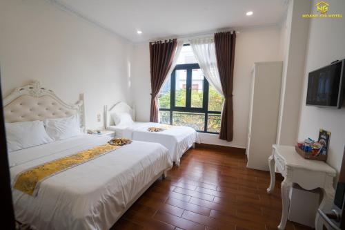 a hotel room with two beds and a window at Hoàng Gia Hotel Tuy Hoà in Tuy Hoa
