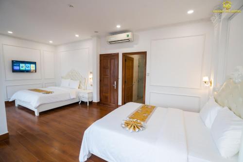 a hotel room with two beds with white sheets at Hoàng Gia Hotel Tuy Hoà in Tuy Hoa