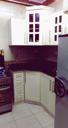 a kitchen with white cabinets and a black counter top at أبراج الـ سعودي شارع الملك فيصل in Cairo