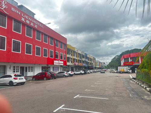 een rood gebouw met auto's geparkeerd op een parkeerplaats bij SiN LiEN HOTEL in Kluang
