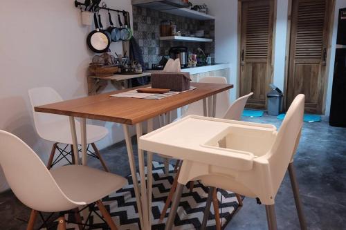 eine Küche mit einem Holztisch und weißen Stühlen in der Unterkunft Homestay Jogja Rumah Obit By Simply Homy in Timuran
