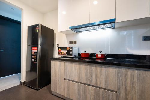 a kitchen with a black refrigerator and a counter at DingD0ng Home FelizEnVista 5-star facilities in Ho Chi Minh City
