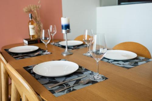 a wooden table with plates and wine glasses on it at DingD0ng Home FelizEnVista 5-star facilities in Ho Chi Minh City