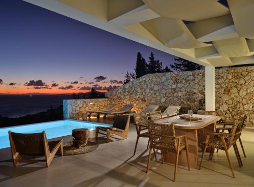 a patio with a table and chairs and a swimming pool at Thelxi's Suite I - Brand New Seaview Suite! in Agios Nikolaos