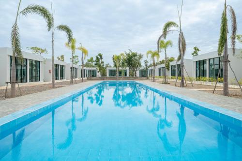 a swimming pool with palm trees and a building at Pran Riverside in Ban Tha Khoi