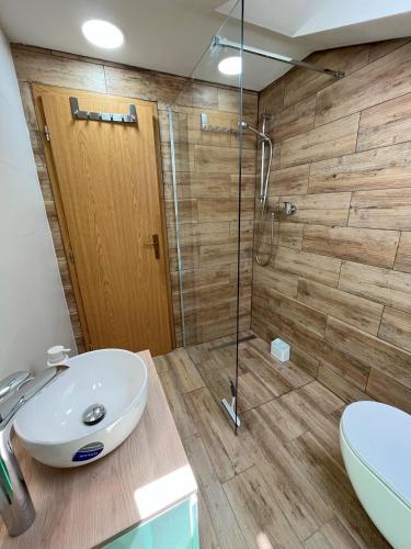 a bathroom with a sink and a glass shower at Penzión Pod Guglom in Mlynky 