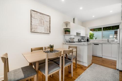 a kitchen and dining room with a wooden table and chairs at Swainson on Penzance in Glenelg