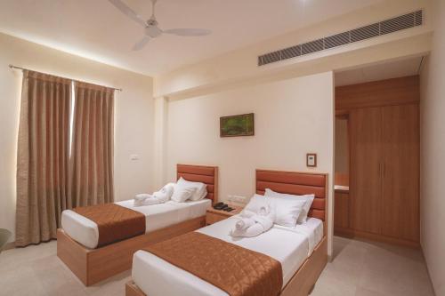 Habitación de hotel con 2 camas y ventana en HOTEL ACHYUT, en Tirupur