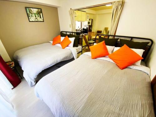 two beds with orange pillows in a room at 1min walk to sta, drct bus to HND! Easy access! 03 in Tokyo