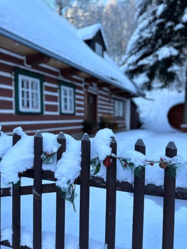 a fence covered in snow in front of a house at Chalupa Šárka in Dolni Dvur
