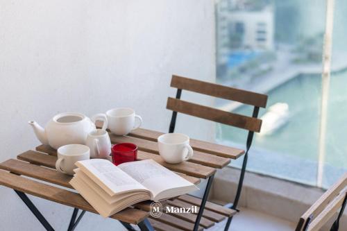 a wooden table with an open book and cups and coffeeisers at Manzil - 1BR Home in Dubai Marina with Marina View, Nr JBR Beach & Marina Mall in Dubai