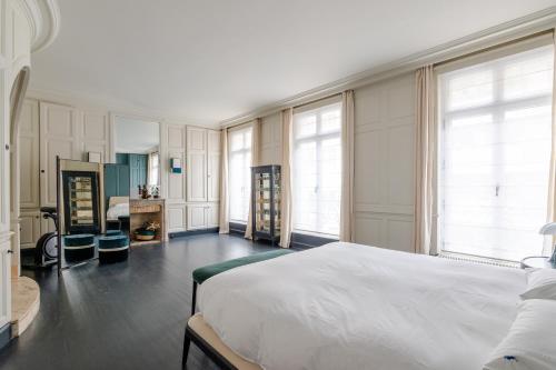 a bedroom with a large white bed and windows at Veeve - Blue Majesty in Paris
