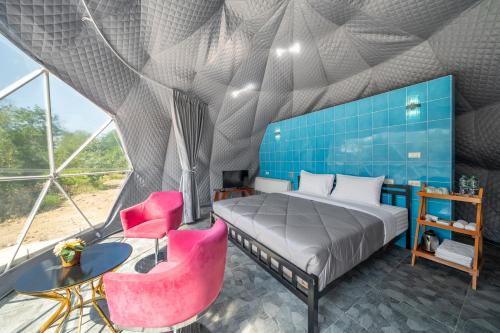a bedroom with a bed and two pink chairs at Pran Riverside in Ban Tha Khoi