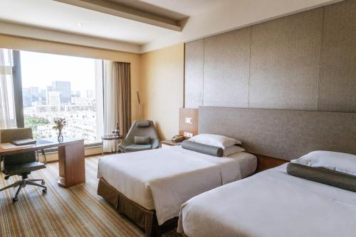 a hotel room with two beds and a desk at Juntai Hotel Xiamen in Xiamen