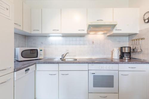 eine weiße Küche mit weißen Schränken und einer Mikrowelle in der Unterkunft Appartementanlage Likedeeler, Ferienwohnung 41 in Boltenhagen
