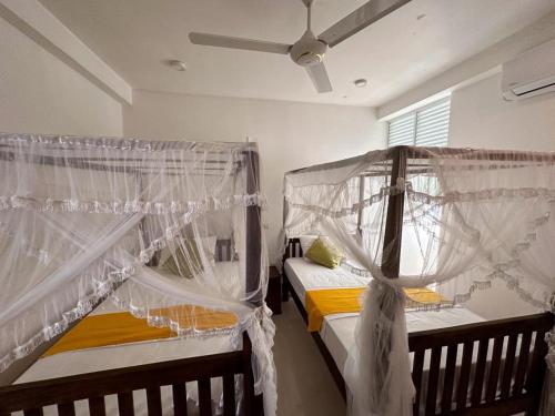 2 camas en una habitación con mosquiteras en VOGEL NEST, en Midigama East
