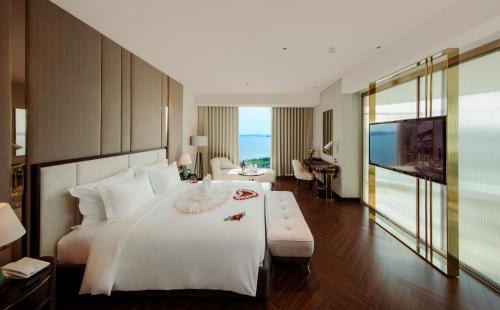a bedroom with a large white bed and a living room at Radisson Blu Ha Long Bay in Ha Long