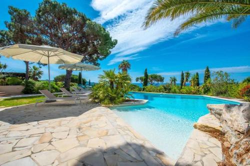 - une piscine avec deux parasols et une plage dans l'établissement Superbe villa avec piscine et vue mer - Villa Capella, à La Croix-Valmer