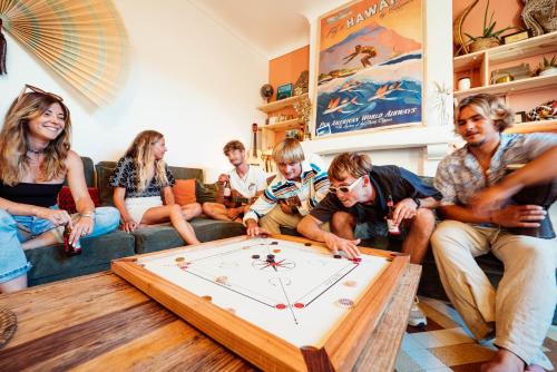 un grupo de personas sentadas en una sala jugando un juego en La Boga L'Auberge à l'ambiance Surf à Biscarrosse Plage, en Biscarrosse-Plage
