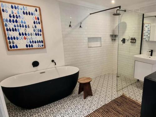 ein Bad mit einer schwarz-weißen Badewanne und einem Waschbecken in der Unterkunft Sun Kiss Beach and Deluxe Garden Cottages in Kapstadt