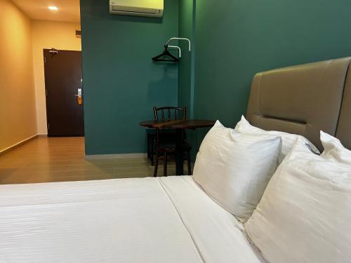 a bedroom with a bed with white pillows and a table at SiN LiEN HOTEL in Kluang