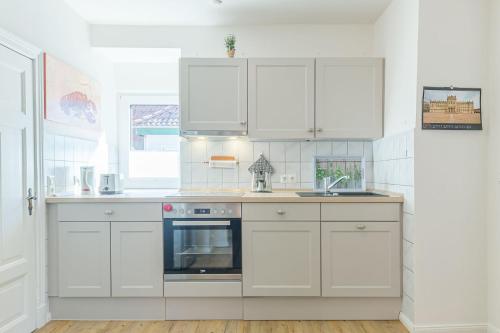 a white kitchen with white cabinets and an oven at Ferienwohnung "Blaues Haus" in Boltenhagen