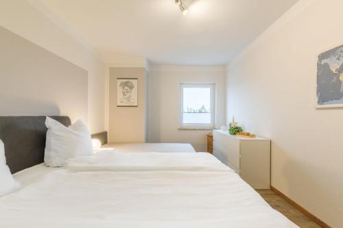 a white bedroom with two beds and a window at Ferienwohnung Erika in Dassow