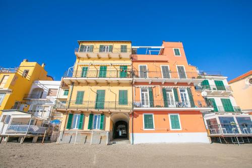 a tall orange building with green shutters at La Casa Sulla Spiaggia - On The Beach- Happy Rentals in Alassio