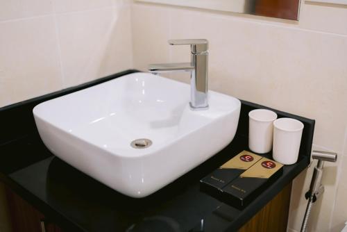 lavabo blanco en una encimera negra en el baño en Cris Inn Tagum, en Tagum