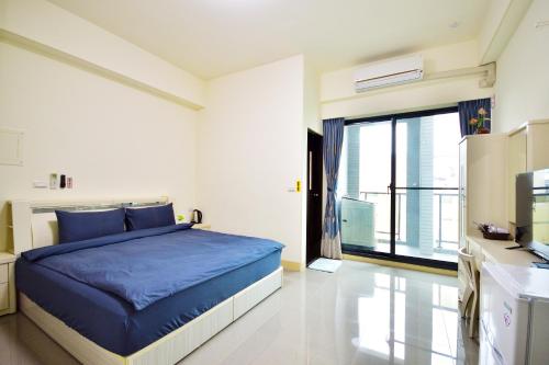a bedroom with a blue bed and a large window at Fengru B&B in Taitung City