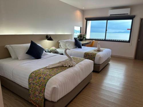 a hotel room with two beds and a large window at Pearl Andaman Resort Ranong Koh Koo 