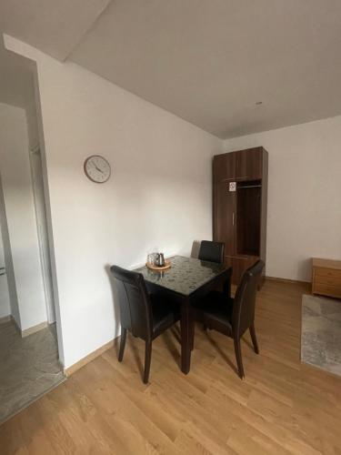 a dining room table with chairs and a clock on a wall at Apartments & Rooms L E F T RIVER Belgrade in Belgrade