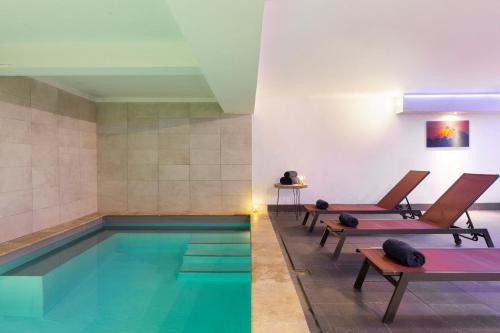 une piscine avec deux chaises et une piscine dans l'établissement SOWELL RESIDENCES Pierre Blanche, aux Menuires