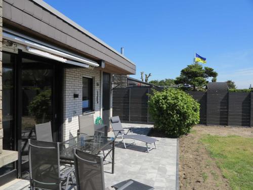 een patio met een glazen tafel en stoelen bij Nordseeferienhaus Tossens III in Butjadingen