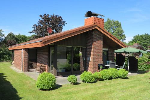 a small brick house with an umbrella in a yard at Ferienlandhaus Schäfer in Tossenserdeich