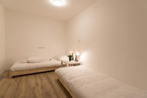 twee bedden in een kamer met witte muren en houten vloeren bij Kampervest Apartment Haarlem in Haarlem