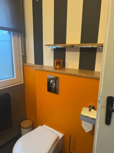 een badkamer met een wit toilet en een oranje muur bij Sol Borsay - Studio de vacances à la campagne - Idéal pour 2 in Comblain-au-Pont