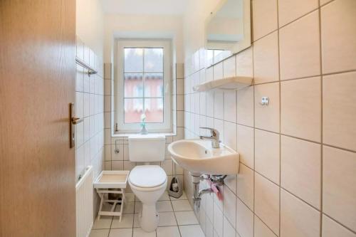 a bathroom with a toilet and a sink and a window at Das Haus Konstantin heißt Sie und Ihre(n) Vierbeiner herzlich willkommen. in Neßmersiel