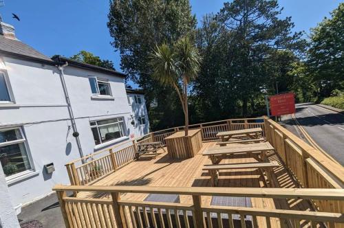 a wooden deck with picnic tables in front of a building at Cottage Court Hotel in Tenby