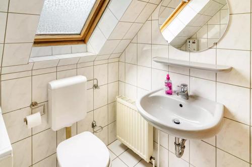 bagno con lavandino, servizi igienici e specchio di Hübsche OG-Wohnung für mx. 3 Personen im Herzen von Neßmersiel a Nessmersiel