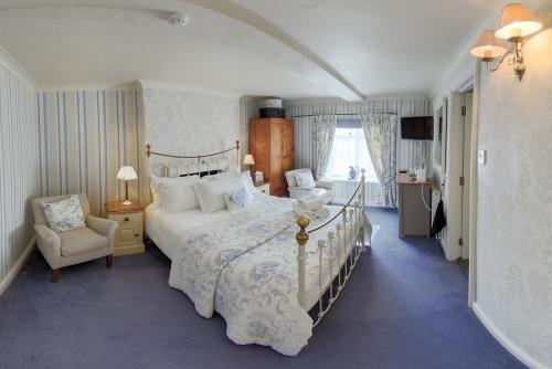 ein Schlafzimmer mit einem großen Bett und einem Stuhl in der Unterkunft The Old Brewhouse in Cirencester