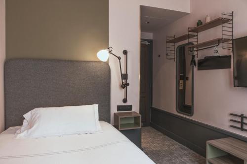 a bedroom with a bed with a mirror and a lamp at Hôtel Des Artistes in Lyon
