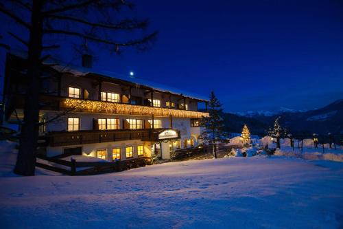 a large building in the snow at night at Hotel-Gasthof Nutzkaser in Ramsau