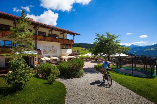 a man riding a bike in front of a building at Hotel-Gasthof Nutzkaser in Ramsau