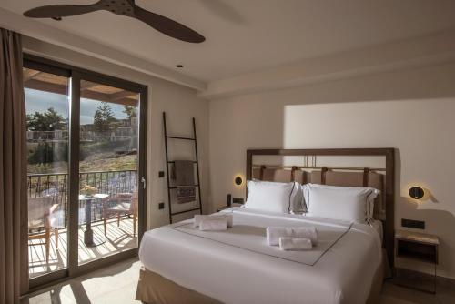 ein Schlafzimmer mit einem großen weißen Bett und einem Balkon in der Unterkunft Elounda Infinity Exclusive Resort & Spa - Adults Only in Elounda